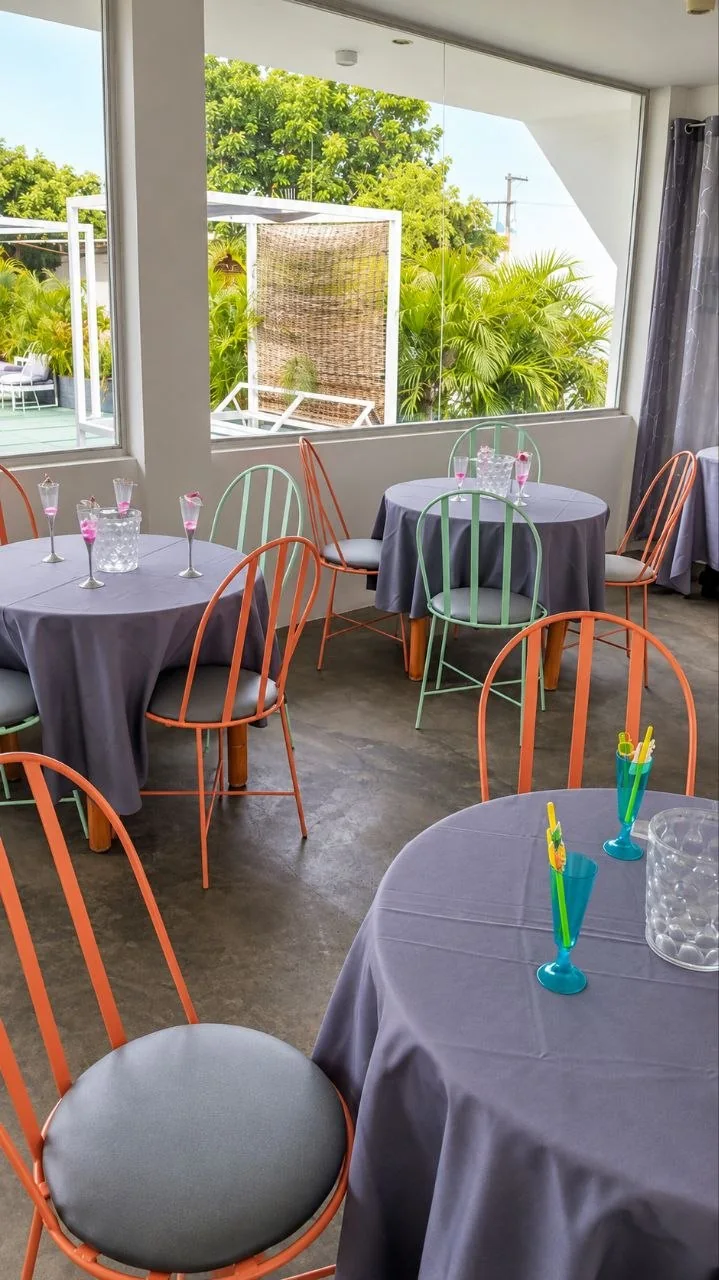 Salón de eventos del hotel con mesas redondas y sillas de colores