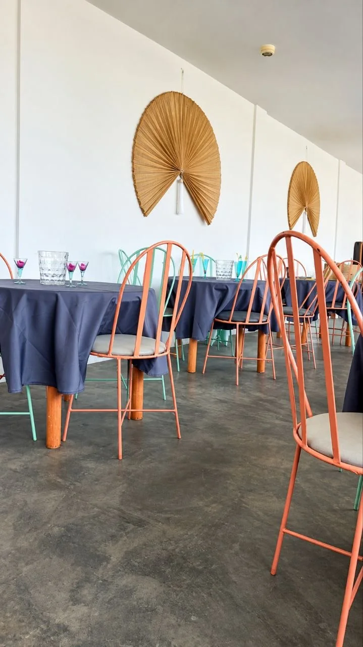 Salón de eventos del hotel con mesas redondas y sillas de colores